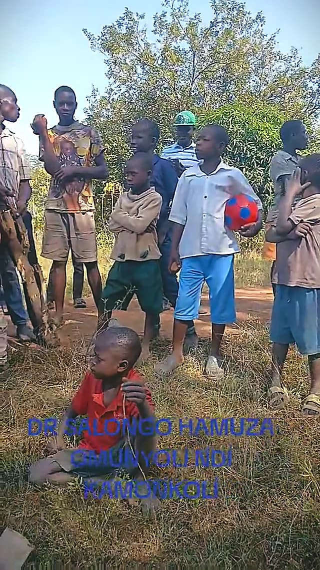 A crowd of neighbours and children standing along a path in an open field